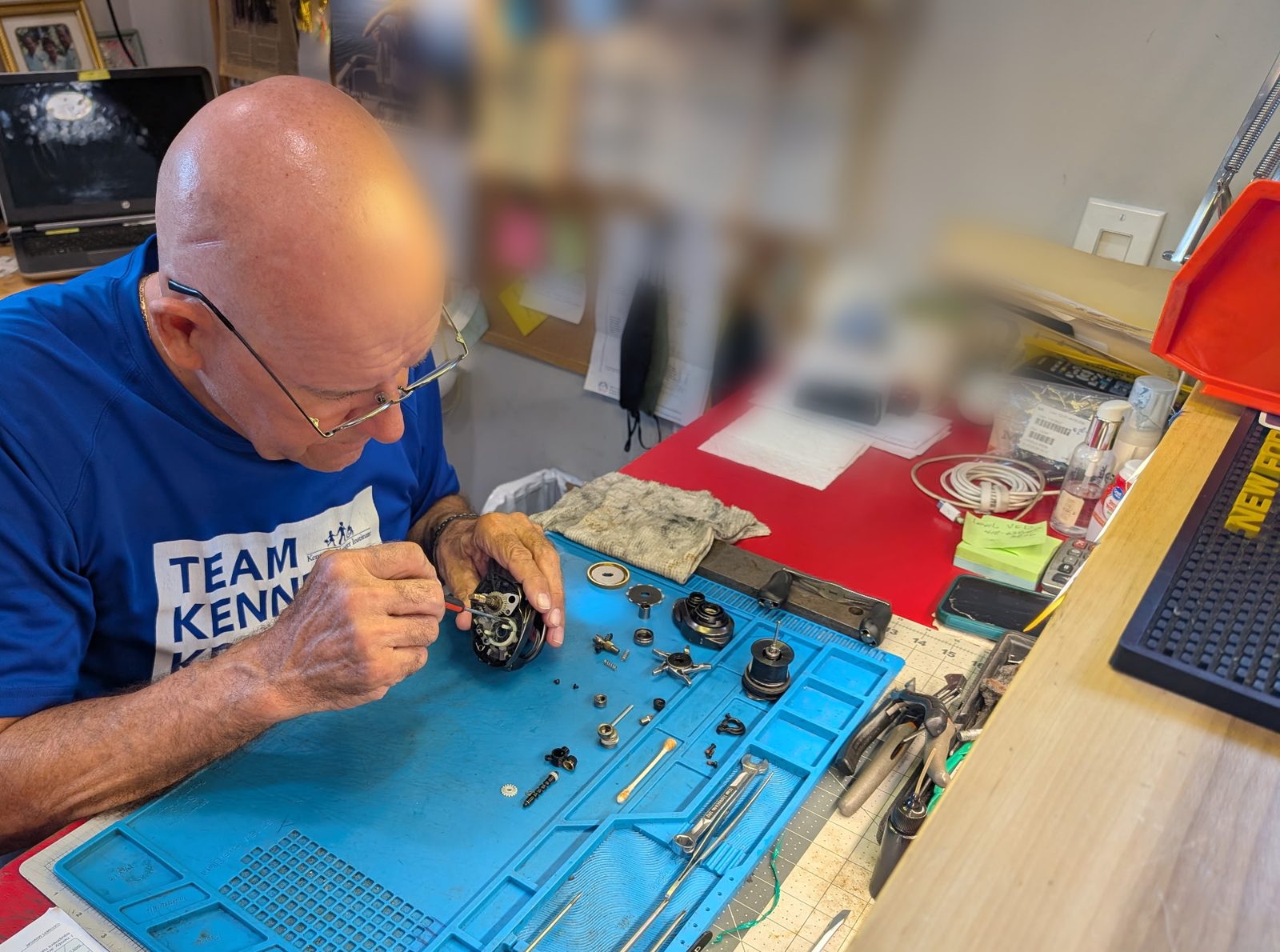 A reel stripped down on the bench at Reel Perfection, parts laid out in order